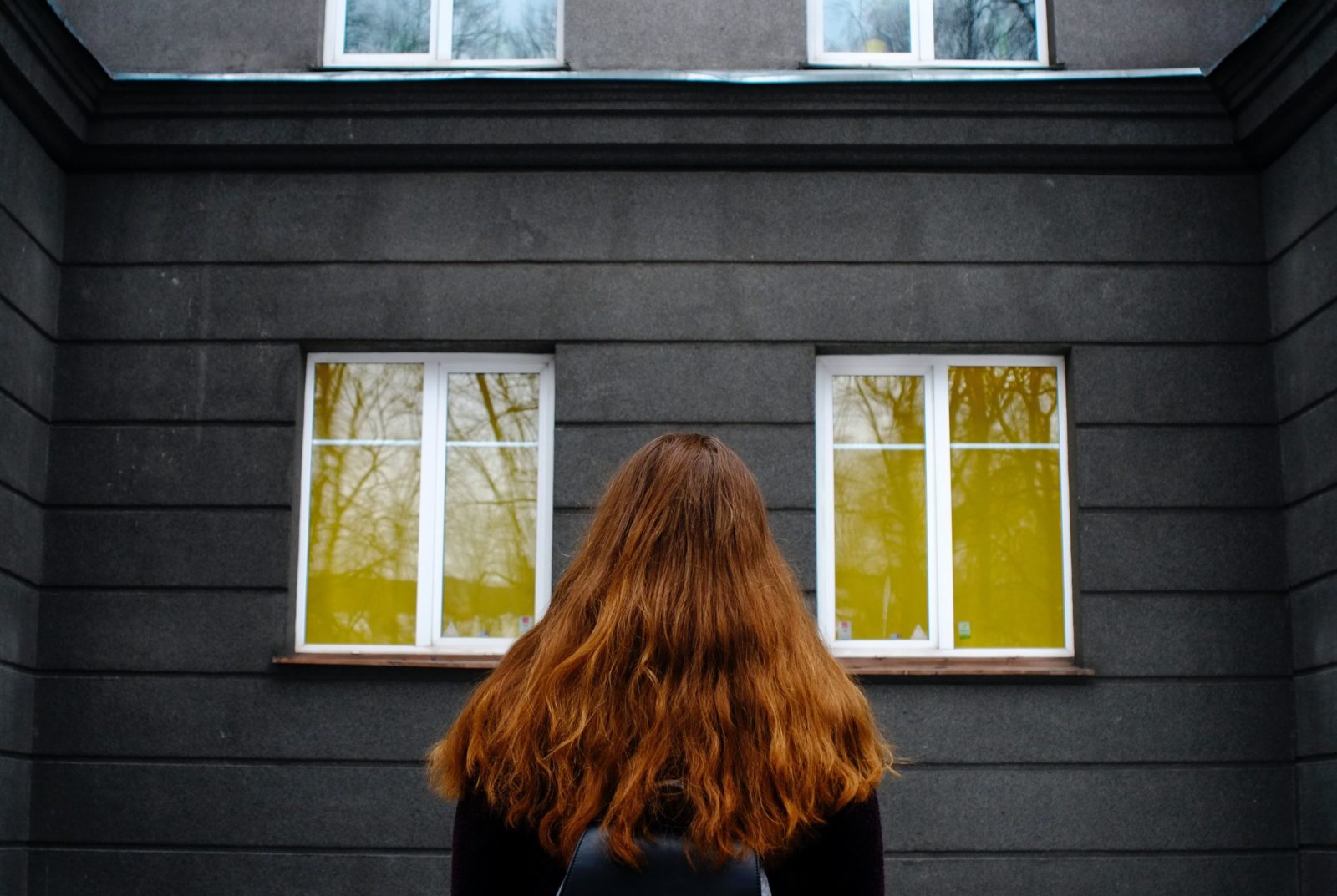 woman in black jacket standing in front of window